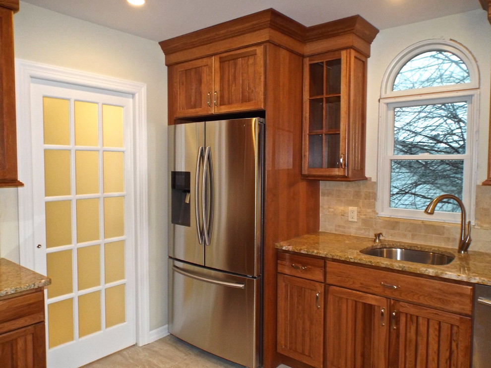 Bild på ett litet lantligt kök, med en nedsänkt diskho, luckor med upphöjd panel, skåp i ljust trä, granitbänkskiva, beige stänkskydd, stänkskydd i stenkakel, rostfria vitvaror, kalkstensgolv och en halv köksö