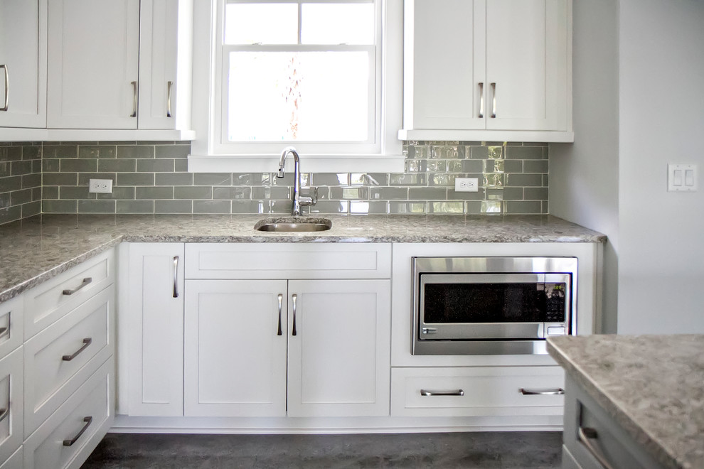 Inspiration for a medium sized coastal l-shaped kitchen/diner in Jacksonville with a submerged sink, shaker cabinets, white cabinets, granite worktops, grey splashback, metro tiled splashback, stainless steel appliances, concrete flooring and an island.