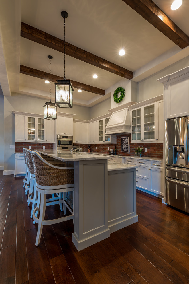 Design ideas for a traditional kitchen in Orlando with a belfast sink, white cabinets, marble worktops, brick splashback, stainless steel appliances and medium hardwood flooring.