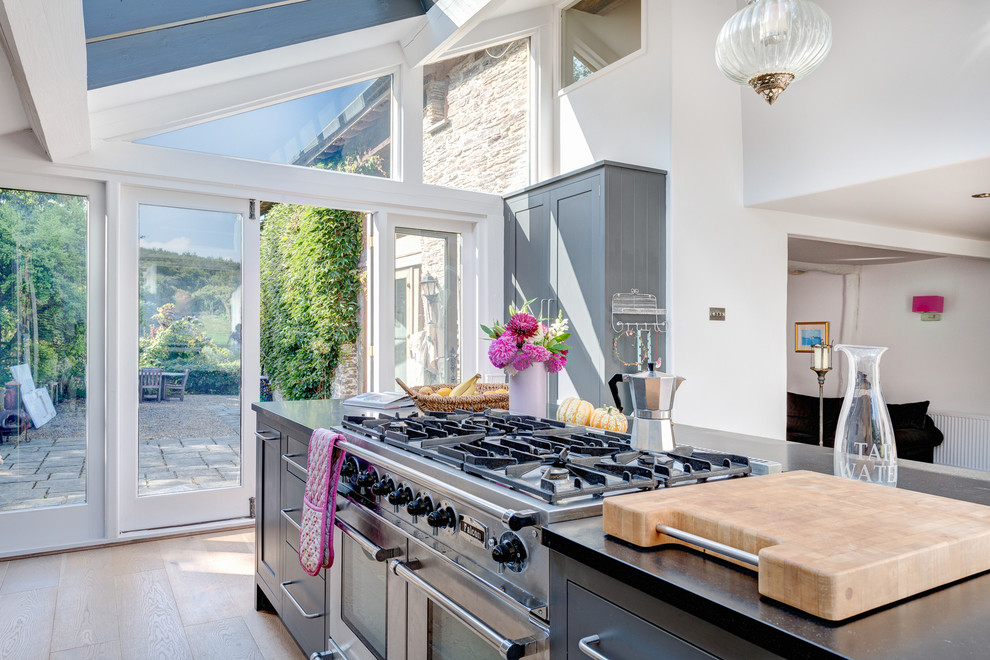 Moderne Wohnküche in U-Form mit flächenbündigen Schrankfronten, grauen Schränken, Granit-Arbeitsplatte und Küchengeräten aus Edelstahl in Devon