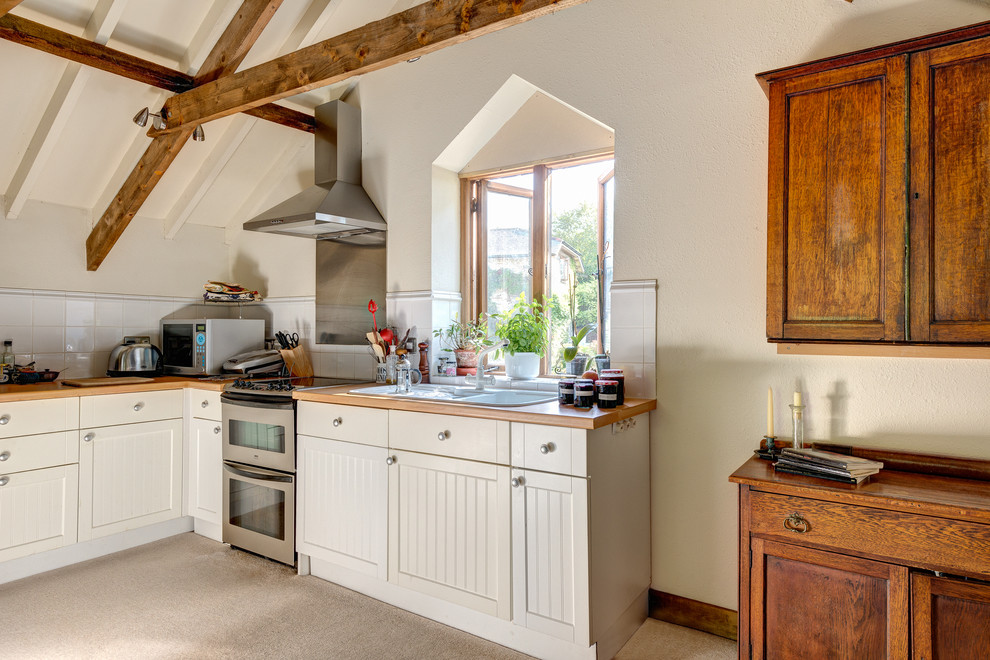This is an example of a country kitchen/diner in Devon with a built-in sink, shaker cabinets, white cabinets, white splashback, stainless steel appliances and porcelain splashback.