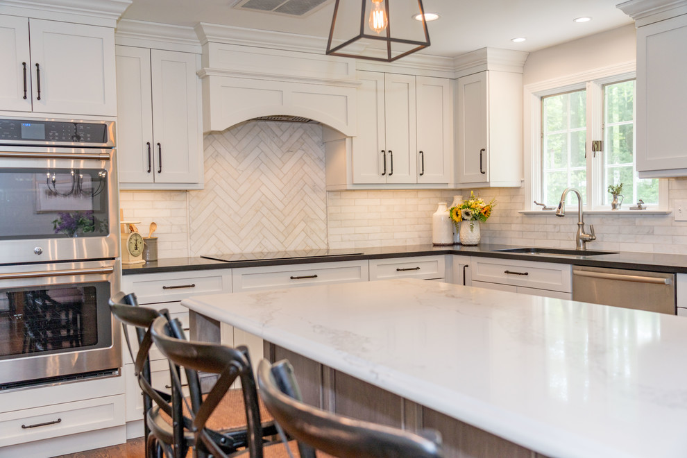 Large cottage l-shaped dark wood floor and brown floor eat-in kitchen photo in Bridgeport with an undermount sink, recessed-panel cabinets, white cabinets, quartz countertops, white backsplash, subway tile backsplash, stainless steel appliances, an island and black countertops