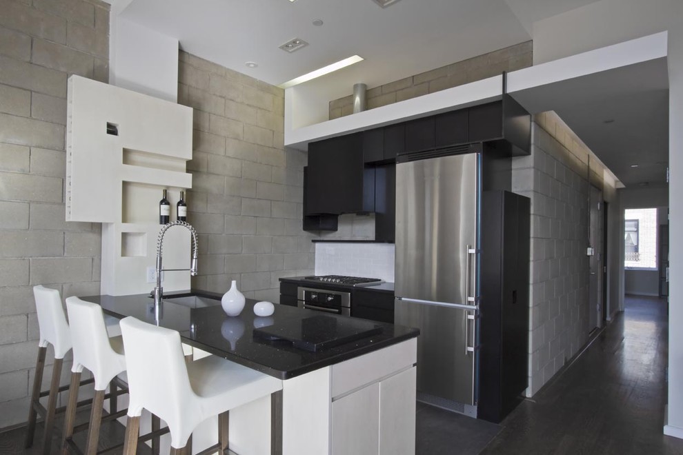 Foto de cocina contemporánea pequeña con armarios con paneles lisos, electrodomésticos de acero inoxidable y encimeras negras