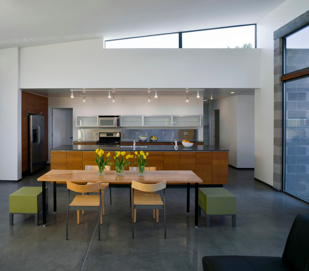 Idée de décoration pour une cuisine minimaliste en bois brun avec un placard à porte plane, un plan de travail en surface solide et sol en béton ciré.