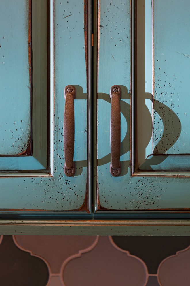 Cette image montre une cuisine américaine bohème avec un évier de ferme, un placard avec porte à panneau surélevé, des portes de placard turquoises, plan de travail en marbre, une crédence grise, une crédence en dalle de pierre et un électroménager en acier inoxydable.