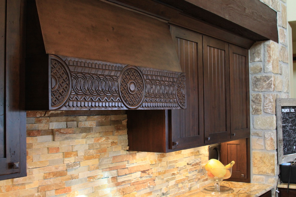 Rustik inredning av ett kök, med en rustik diskho, luckor med profilerade fronter, skåp i mörkt trä, granitbänkskiva, rostfria vitvaror, betonggolv och en halv köksö