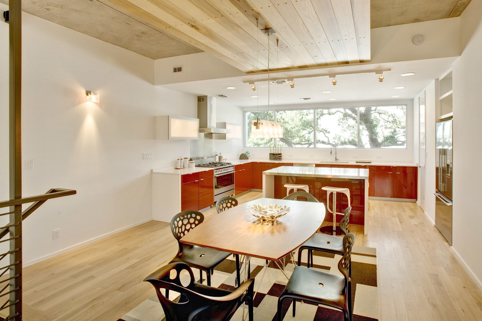 Источник вдохновения для домашнего уюта: угловая кухня в современном стиле с красными фасадами, обеденным столом, плоскими фасадами и техникой из нержавеющей стали