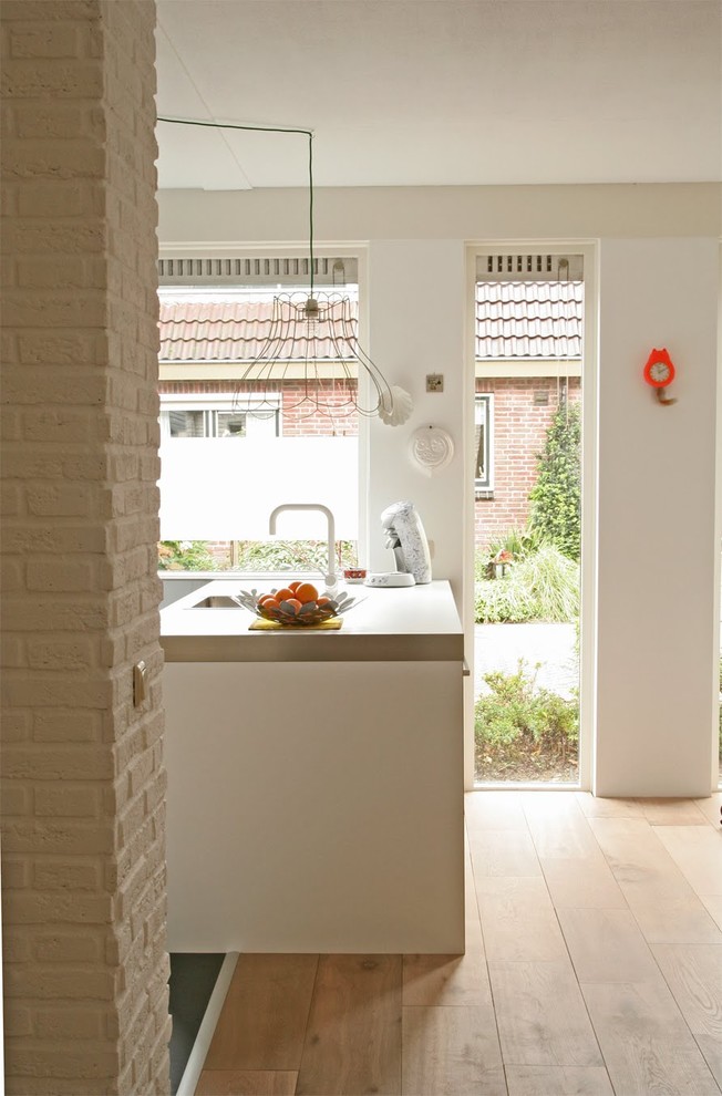 Moderne Küche mit Waschbecken und weißen Schränken in Amsterdam