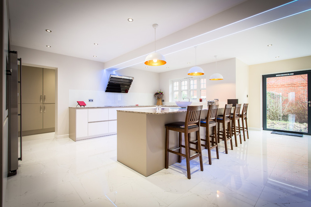 Inspiration for a medium sized contemporary u-shaped open plan kitchen in Hampshire with white cabinets, stainless steel appliances, an island, an integrated sink, flat-panel cabinets, granite worktops, white splashback and glass sheet splashback.