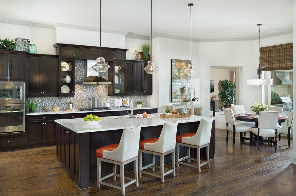Inspiration for a large galley medium tone wood floor open concept kitchen remodel in Tampa with an undermount sink, recessed-panel cabinets, dark wood cabinets, quartzite countertops, gray backsplash, metal backsplash, stainless steel appliances and an island