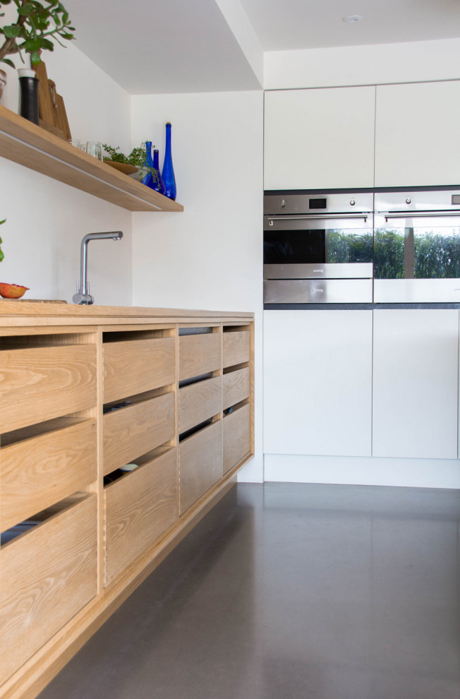 Inspiration for a large scandi galley open plan kitchen in Other with a double-bowl sink, open cabinets, light wood cabinets, wood worktops, stainless steel appliances, an island and grey floors.