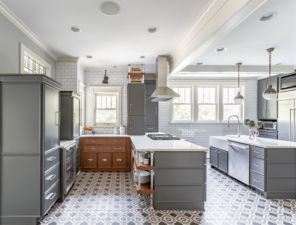 This is an example of a traditional kitchen in Chicago with a belfast sink, grey cabinets, white splashback, metro tiled splashback, stainless steel appliances and multiple islands.