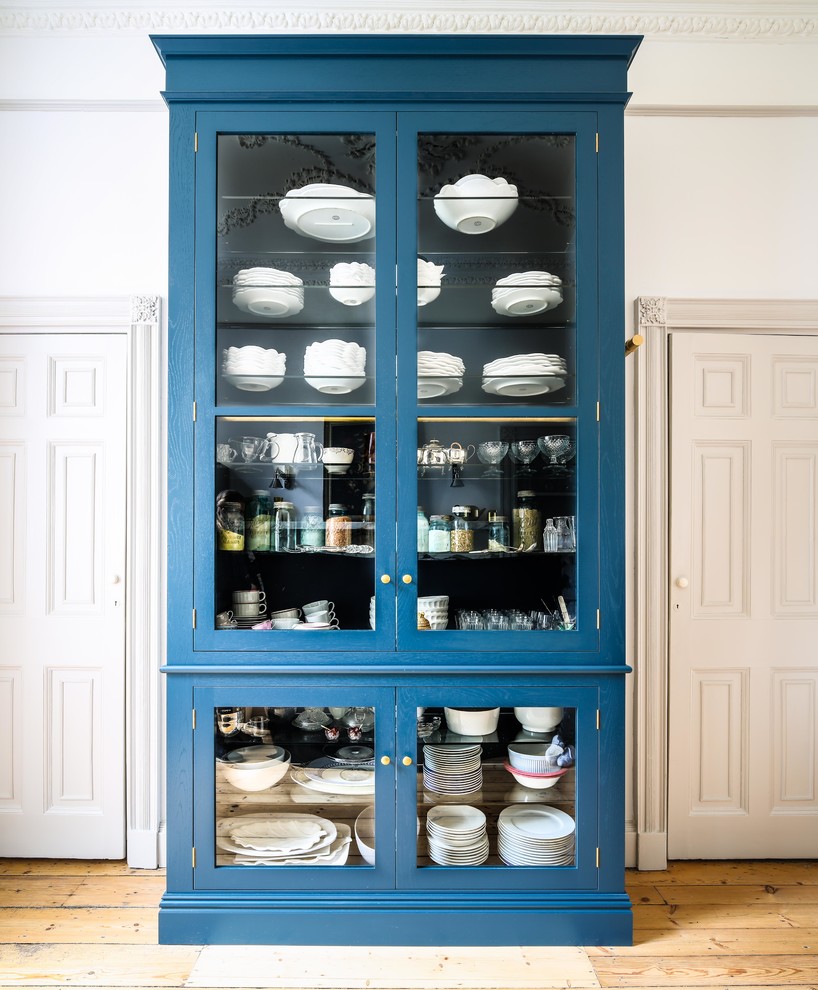 Diseño de cocina clásica de tamaño medio sin isla con armarios tipo vitrina, puertas de armario azules y suelo de madera clara