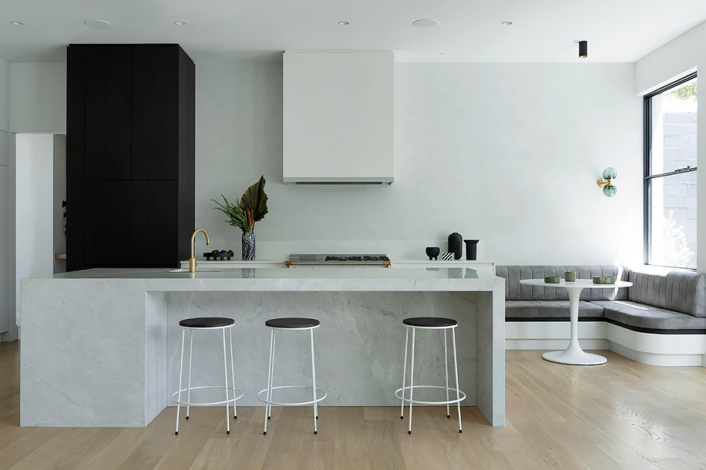 Inspiration för stora moderna vitt kök, med vita skåp, marmorbänkskiva, vitt stänkskydd, rostfria vitvaror, mellanmörkt trägolv, en köksö och brunt golv