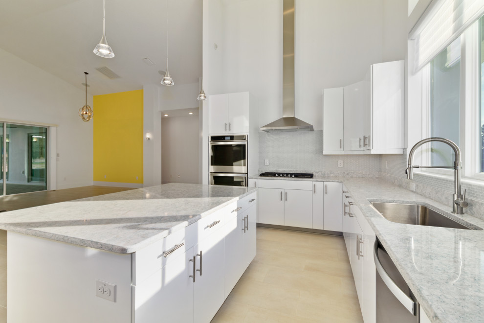 Example of a large 1960s u-shaped porcelain tile and white floor kitchen design in Other with a single-bowl sink, flat-panel cabinets, white cabinets, quartz countertops, glass tile backsplash, stainless steel appliances, an island and turquoise countertops