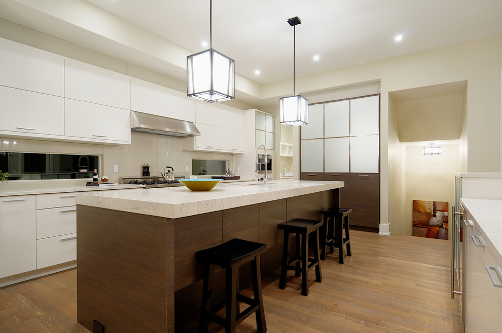 Exempel på ett modernt kök, med släta luckor, marmorbänkskiva, rostfria vitvaror, vita skåp och vitt stänkskydd