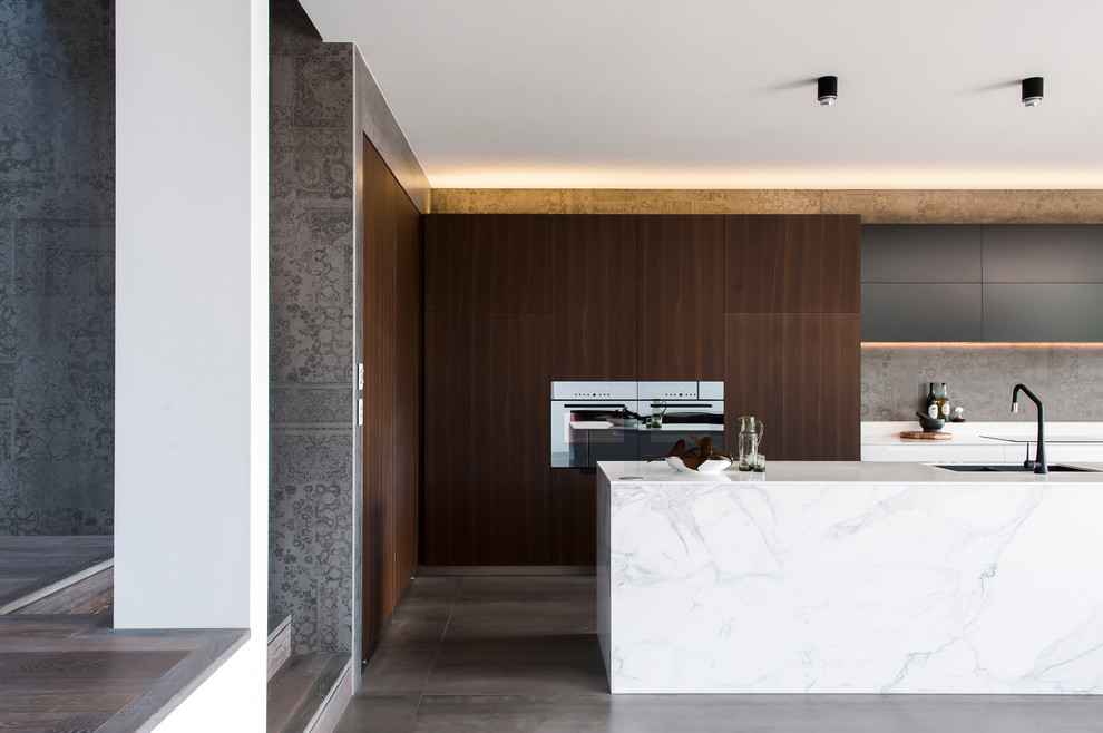 Mittelgroße Moderne Wohnküche in L-Form mit integriertem Waschbecken, dunklen Holzschränken, Mineralwerkstoff-Arbeitsplatte, Küchenrückwand in Grau, Rückwand aus Zementfliesen, schwarzen Elektrogeräten, Keramikboden und Kücheninsel in Sydney