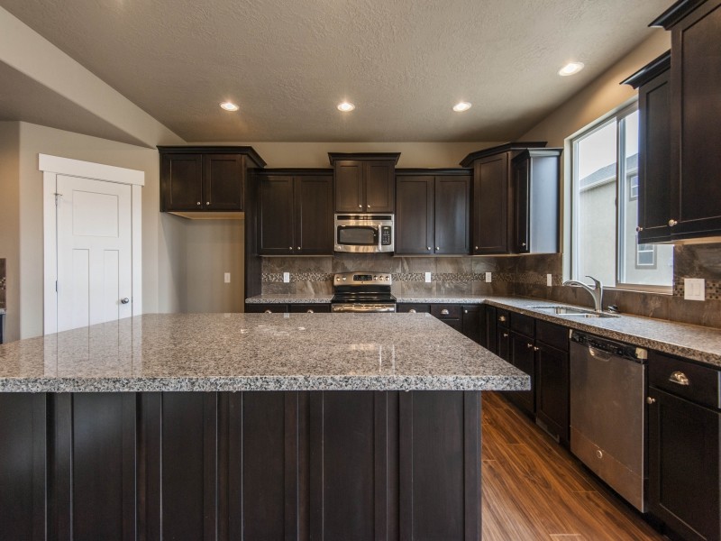 Eat-in kitchen - traditional u-shaped eat-in kitchen idea in Salt Lake City with shaker cabinets, dark wood cabinets, an undermount sink, granite countertops, gray backsplash and stainless steel appliances