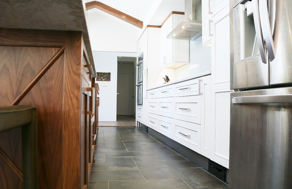 Foto på ett mellanstort 50 tals kök, med luckor med infälld panel, skåp i ljust trä, bänkskiva i kvarts, rostfria vitvaror och flera köksöar