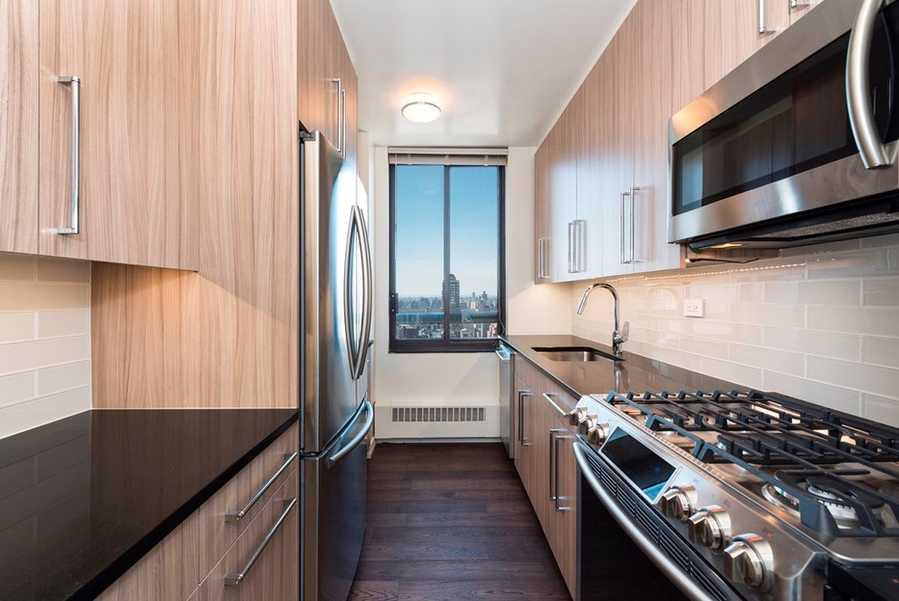 This is an example of a small contemporary galley eat-in kitchen in New York with an undermount sink, flat-panel cabinets, light wood cabinets, quartz benchtops, grey splashback, subway tile splashback, stainless steel appliances, dark hardwood floors and no island.