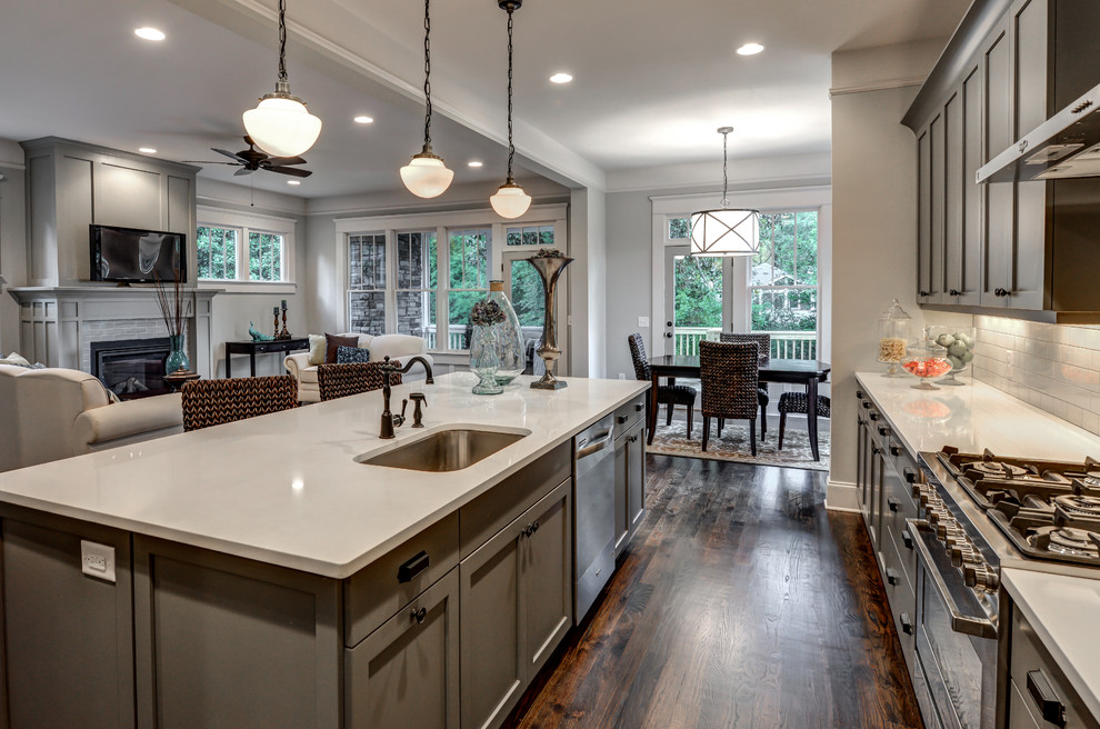 Inspiration for a large traditional galley open plan kitchen in Atlanta with a submerged sink, shaker cabinets, grey cabinets, engineered stone countertops, white splashback, ceramic splashback, stainless steel appliances, dark hardwood flooring and an island.