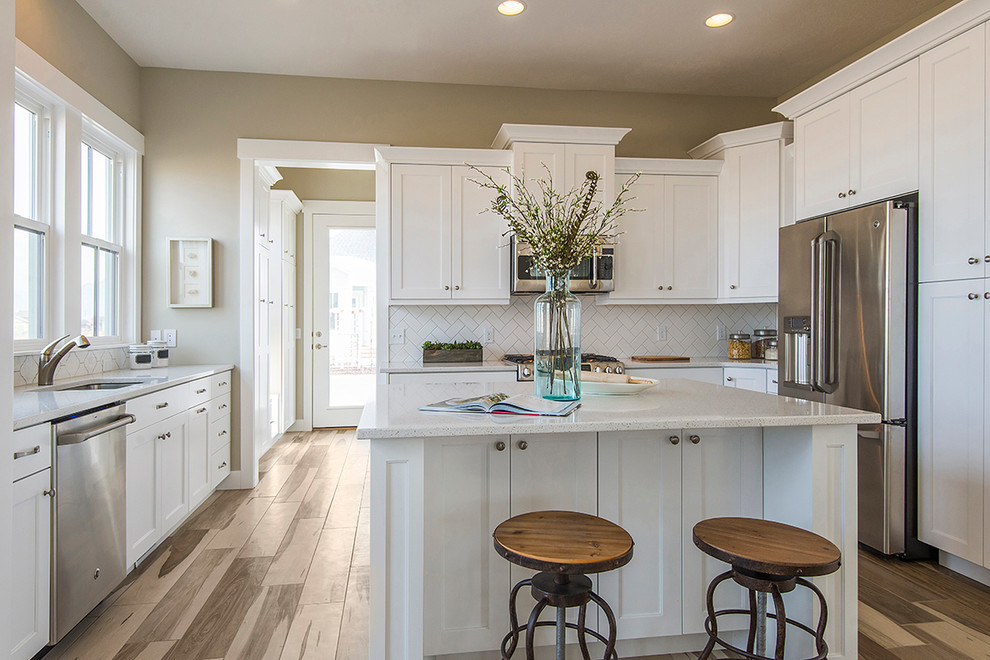 Photo of a classic u-shaped kitchen in Salt Lake City with a submerged sink, shaker cabinets, white cabinets, white splashback, stainless steel appliances and medium hardwood flooring.
