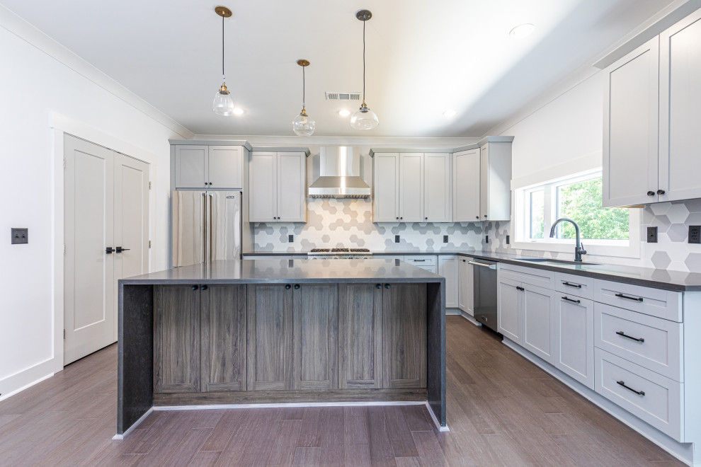 Example of a trendy l-shaped kitchen design in Atlanta with an undermount sink, shaker cabinets, medium tone wood cabinets, quartz countertops, multicolored backsplash, porcelain backsplash, stainless steel appliances, an island and black countertops