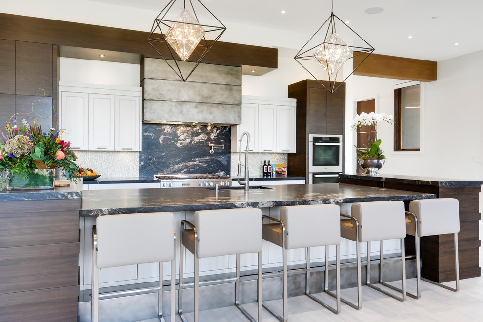 Trendy galley gray floor kitchen photo in Calgary with an undermount sink, shaker cabinets, white cabinets, black backsplash, stone slab backsplash, stainless steel appliances and an island