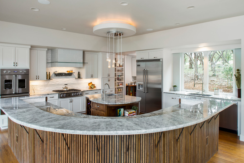 Large traditional l-shaped enclosed kitchen in Austin with a submerged sink, shaker cabinets, white cabinets, white splashback, matchstick tiled splashback, stainless steel appliances, medium hardwood flooring, multiple islands and beige floors.