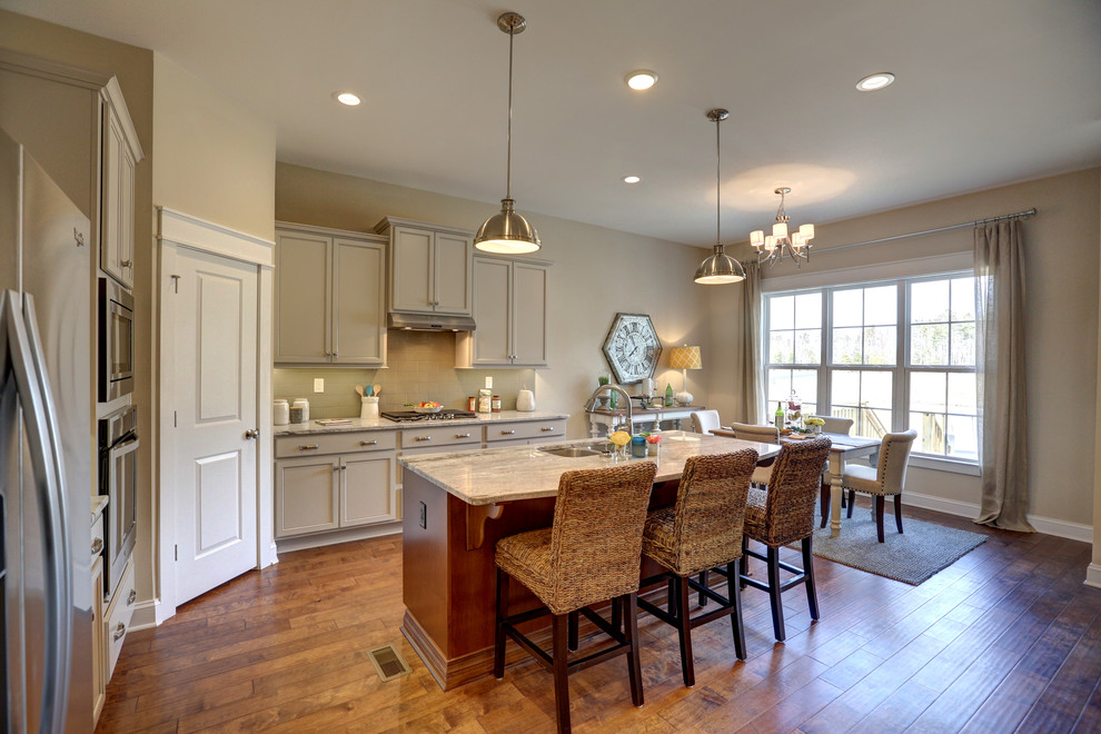 Example of a large transitional galley medium tone wood floor open concept kitchen design in Richmond with a drop-in sink, recessed-panel cabinets, gray cabinets, granite countertops, beige backsplash, glass tile backsplash, stainless steel appliances and an island