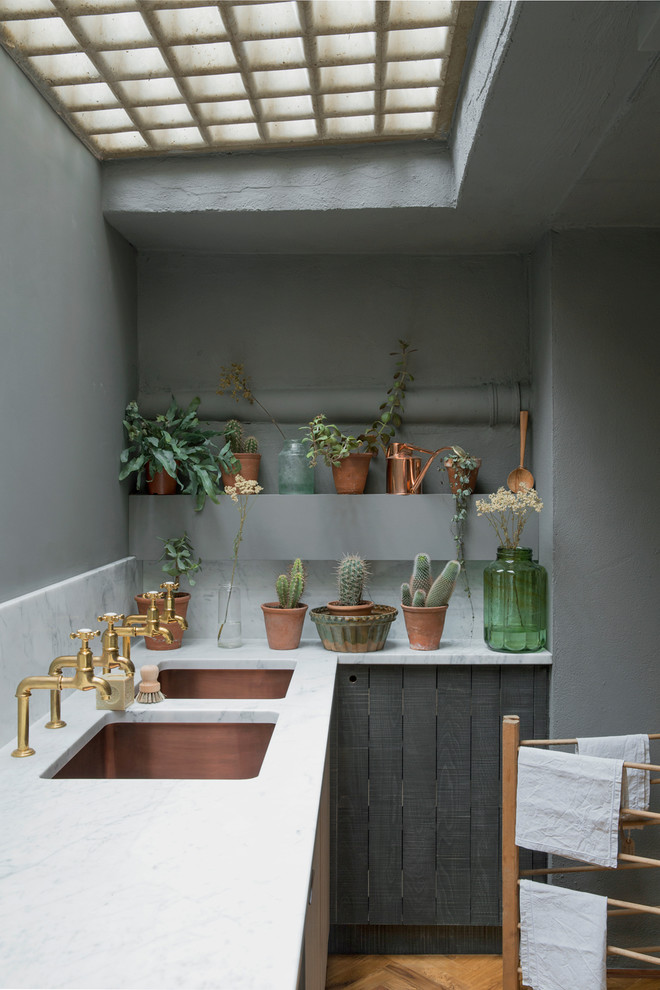Esempio di una cucina industriale chiusa e di medie dimensioni con lavello a doppia vasca, top in marmo, elettrodomestici in acciaio inossidabile, pavimento in legno massello medio e ante nere