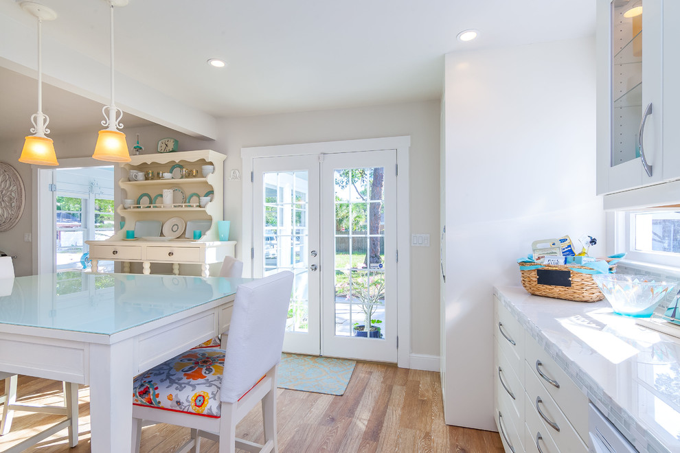 Inspiration for a small shabby-chic style l-shaped light wood floor kitchen remodel in Tampa with a single-bowl sink, shaker cabinets, white cabinets, tile countertops, multicolored backsplash, glass sheet backsplash and white appliances