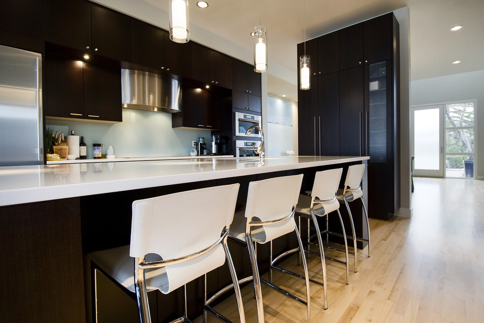 Design ideas for a contemporary kitchen in Calgary with flat-panel cabinets, dark wood cabinets and glass sheet splashback.