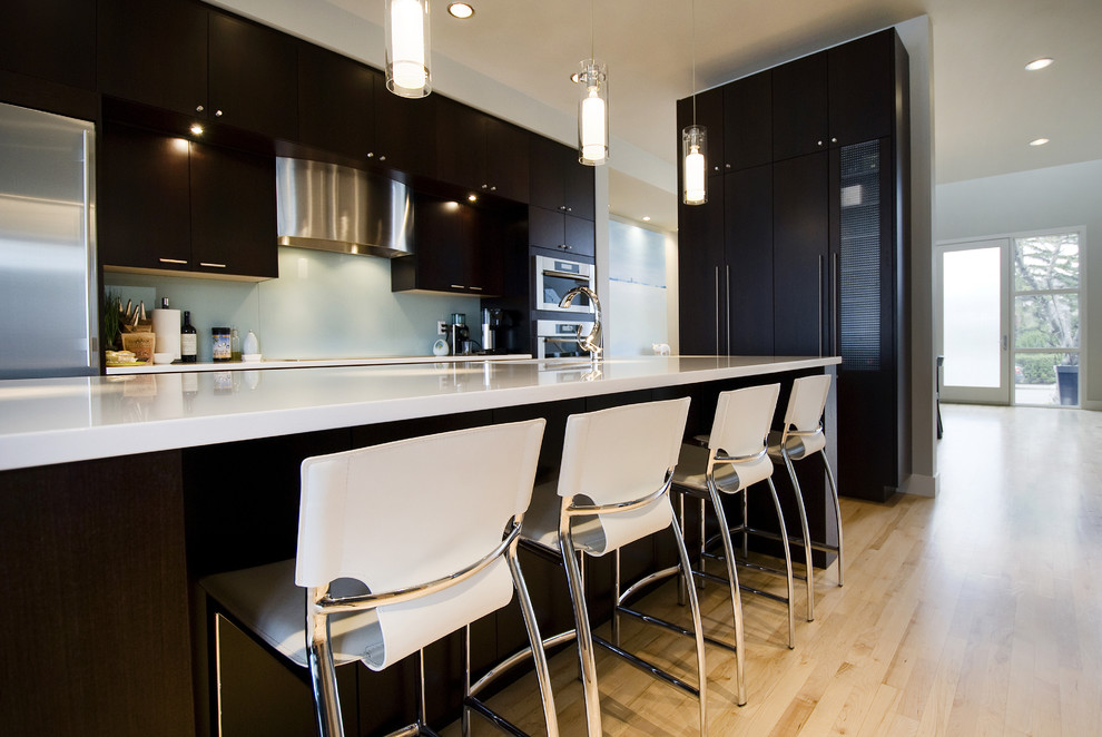 Trendy kitchen photo in Calgary with flat-panel cabinets, dark wood cabinets and glass sheet backsplash