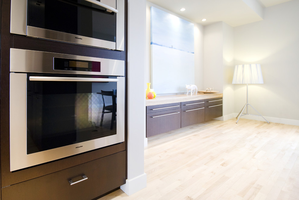 Exemple d'une cuisine tendance en bois foncé avec un placard à porte plane et un électroménager en acier inoxydable.