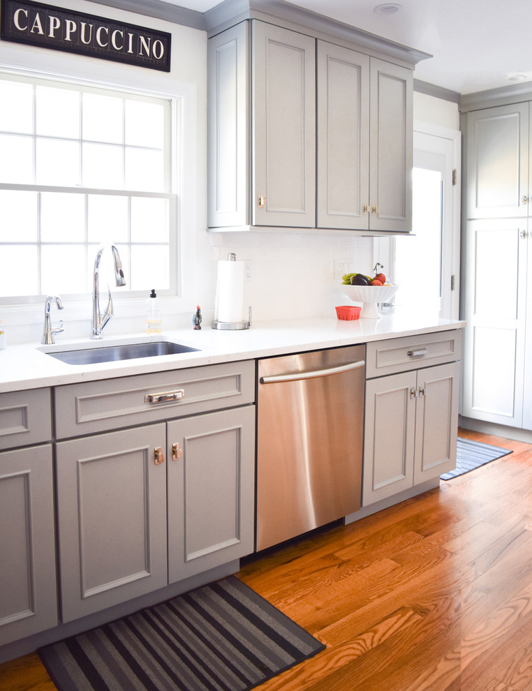 Small nautical l-shaped kitchen/diner in New York with a submerged sink, recessed-panel cabinets, blue cabinets, engineered stone countertops, white splashback, metro tiled splashback, stainless steel appliances and medium hardwood flooring.