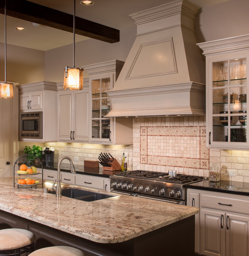Imagen de cocinas en L clásica, de tamaño medio, abierta, con fregadero bajoencimera, armarios con paneles con relieve, puertas de armario beige, encimera de granito, salpicadero beige, salpicadero de azulejos de piedra, electrodomésticos de acero inoxidable, suelo de madera oscura y una isla