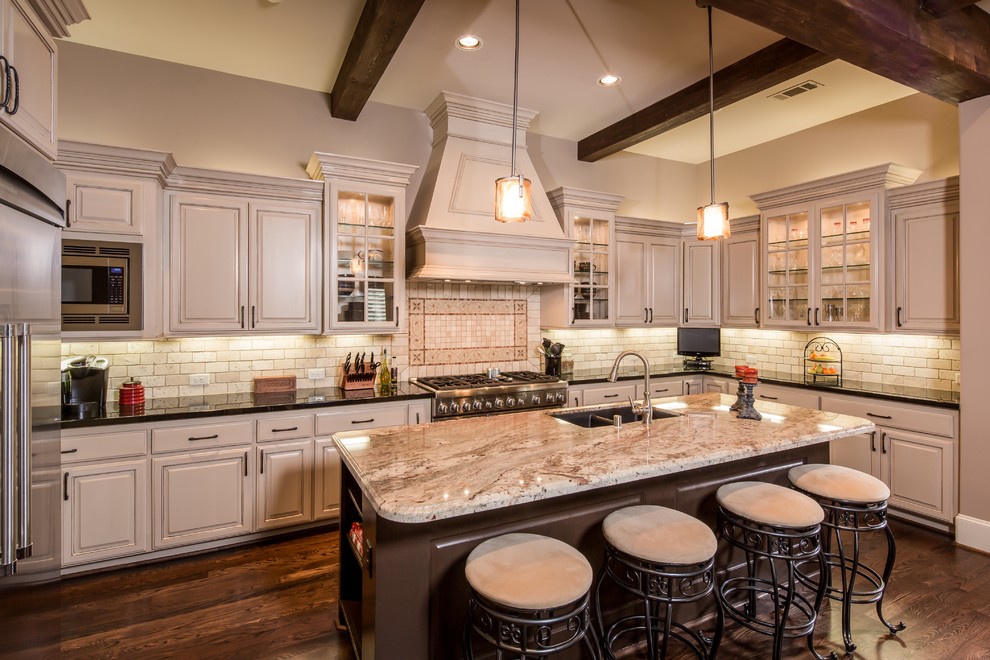 Design ideas for a medium sized traditional l-shaped open plan kitchen in Houston with a submerged sink, raised-panel cabinets, beige cabinets, granite worktops, beige splashback, stone tiled splashback, stainless steel appliances, dark hardwood flooring and an island.