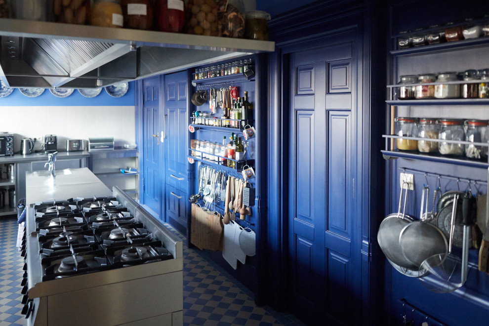 Inredning av ett klassiskt avskilt grå grått kök, med blå skåp, bänkskiva i rostfritt stål, rostfria vitvaror, klinkergolv i terrakotta och blått golv