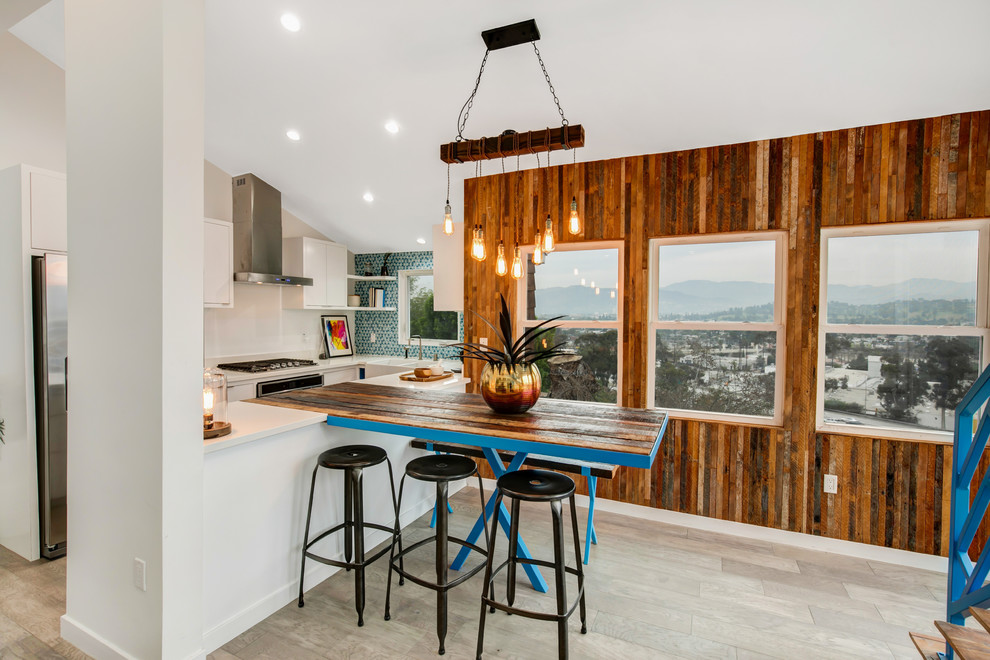 Eat-in kitchen - coastal u-shaped beige floor eat-in kitchen idea in Los Angeles with a farmhouse sink, flat-panel cabinets, white cabinets, blue backsplash, mosaic tile backsplash, stainless steel appliances, a peninsula and white countertops