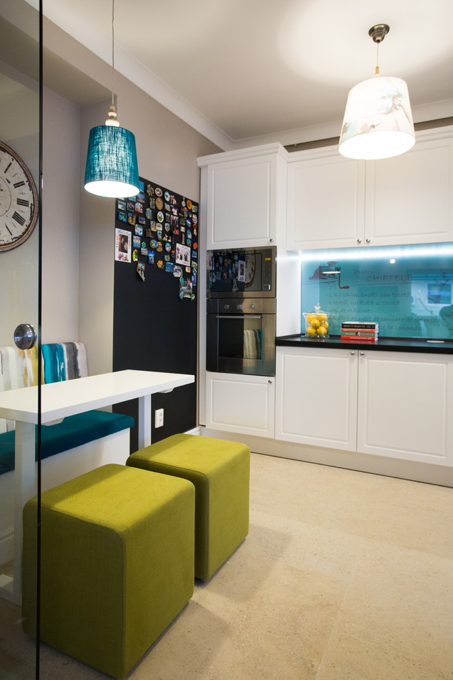Ejemplo de cocina comedor actual con puertas de armario blancas, salpicadero azul y electrodomésticos de acero inoxidable