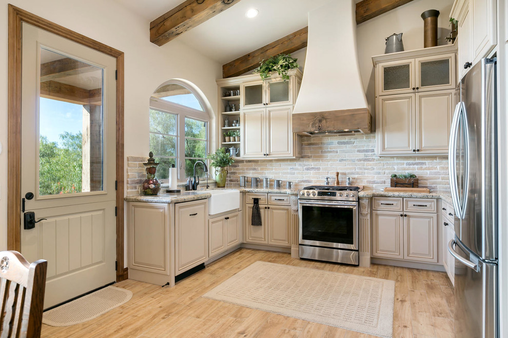 Tuscan u-shaped light wood floor eat-in kitchen photo in San Diego with a farmhouse sink, raised-panel cabinets, beige cabinets, multicolored backsplash, brick backsplash, stainless steel appliances, no island and multicolored countertops