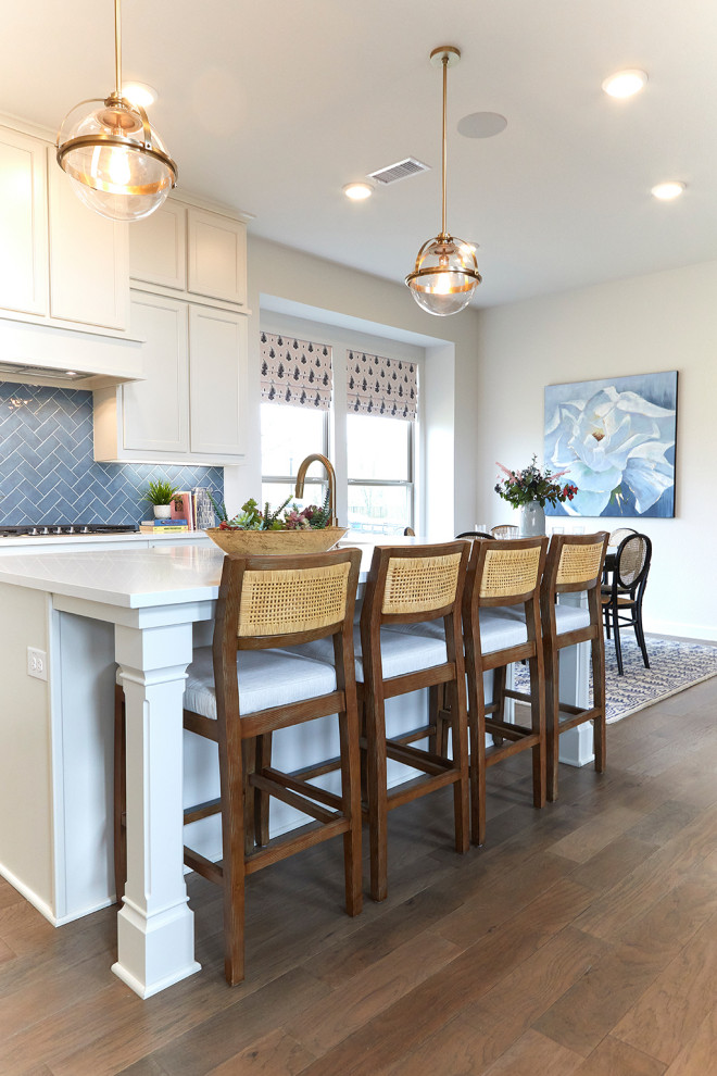Imagen de cocina comedor clásica renovada de tamaño medio con puertas de armario blancas, salpicadero azul, una isla, suelo marrón y encimeras blancas