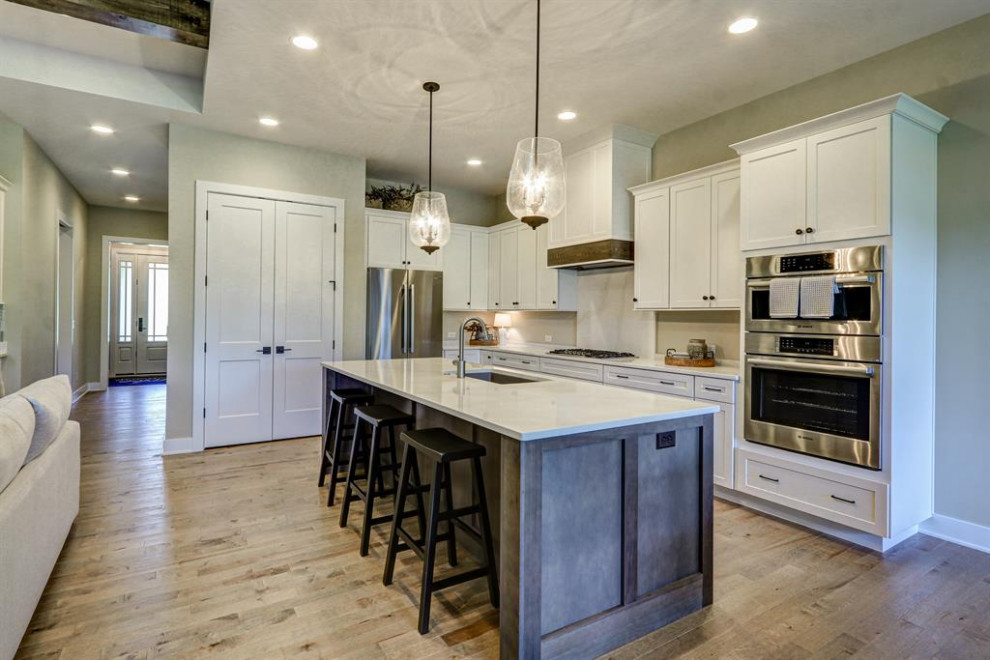 Inspiration for a large transitional l-shaped dark wood floor eat-in kitchen remodel in Cincinnati with raised-panel cabinets, white cabinets, beige backsplash, stainless steel appliances, an island and beige countertops