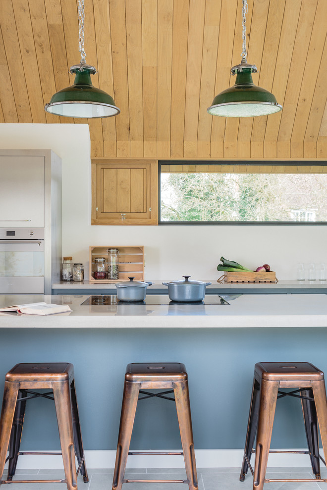 Foto på ett stort funkis kök, med en dubbel diskho, släta luckor, grå skåp, bänkskiva i betong, rostfria vitvaror och en köksö