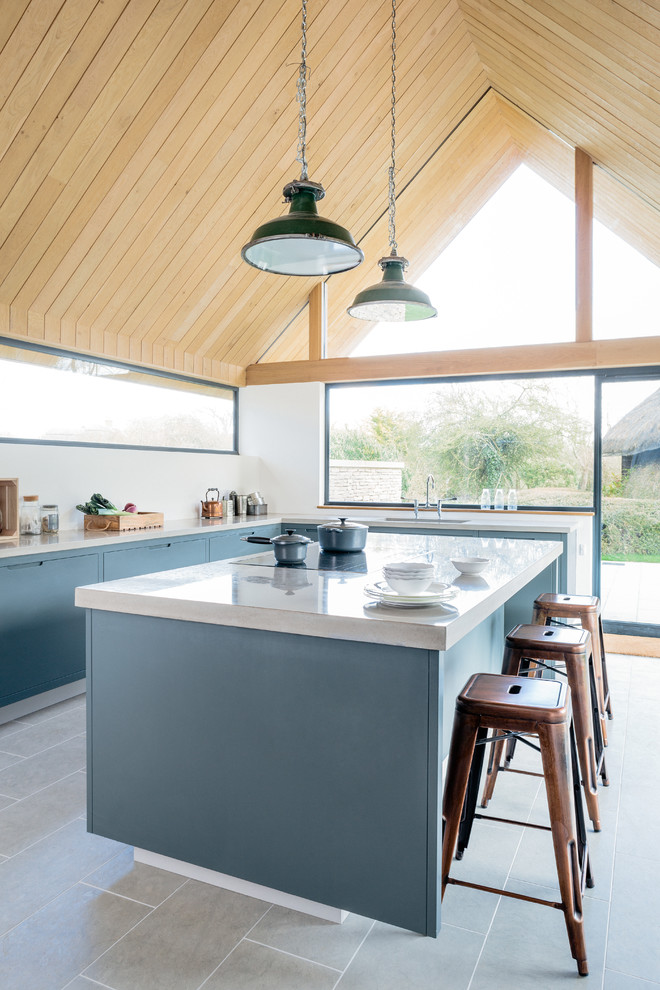 This is an example of a large contemporary l-shaped kitchen/diner in Wiltshire with a double-bowl sink, flat-panel cabinets, grey cabinets, concrete worktops, stainless steel appliances and an island.