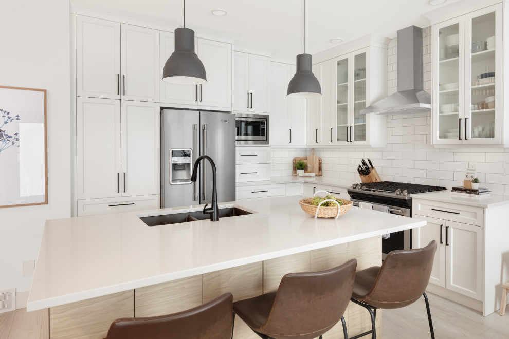Small danish l-shaped vinyl floor and multicolored floor eat-in kitchen photo in Vancouver with an undermount sink, shaker cabinets, white cabinets, quartzite countertops, white backsplash, ceramic backsplash, stainless steel appliances, an island and white countertops