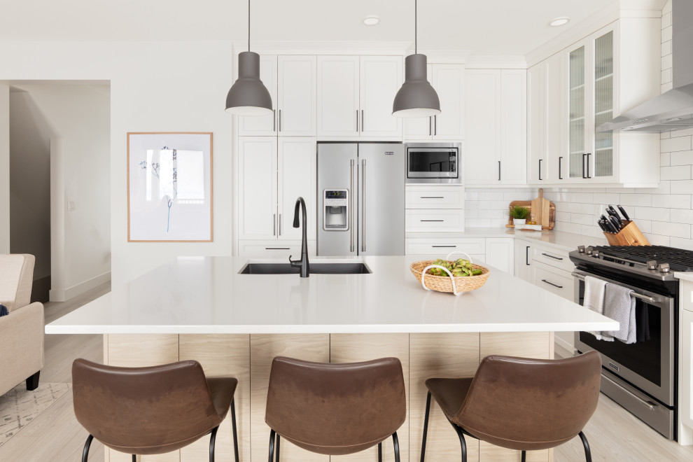 Eat-in kitchen - small scandinavian l-shaped vinyl floor and multicolored floor eat-in kitchen idea in Vancouver with an undermount sink, shaker cabinets, white cabinets, quartzite countertops, white backsplash, ceramic backsplash, stainless steel appliances, an island and white countertops