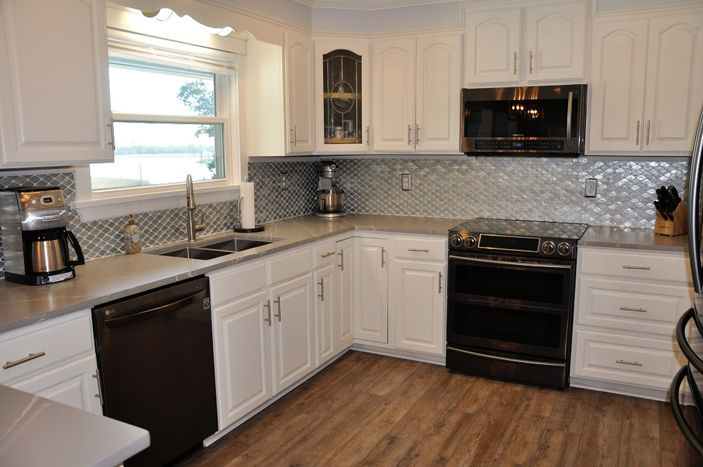Foto på ett funkis grå kök, med en undermonterad diskho, vita skåp, bänkskiva i kvarts, grått stänkskydd, stänkskydd i glaskakel och en köksö