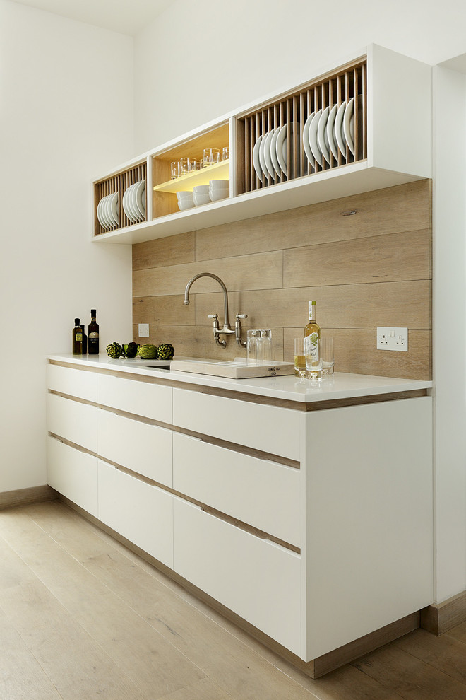 Ejemplo de cocina lineal nórdica con armarios con paneles lisos, puertas de armario blancas y encimera de acrílico